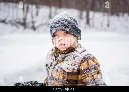 Portrait d'un garçon assis dans la neige, Wisconsin, United States Banque D'Images