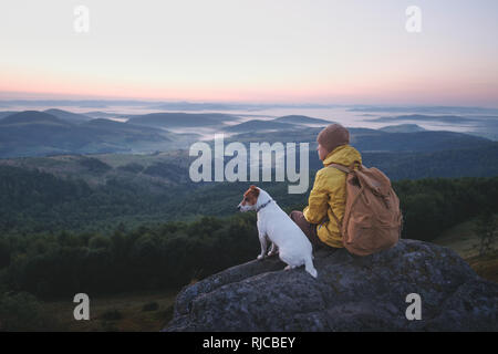 Tourisme à elle seule assise sur le bord de la falaise avec chien dans le contexte d'un incroyable paysage de montagne. Journée ensoleillée et ciel bleu Banque D'Images