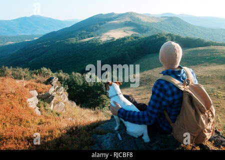 Tourisme à elle seule assise sur le bord de la falaise avec chien dans le contexte d'un incroyable paysage de montagne. Journée ensoleillée et ciel bleu Banque D'Images