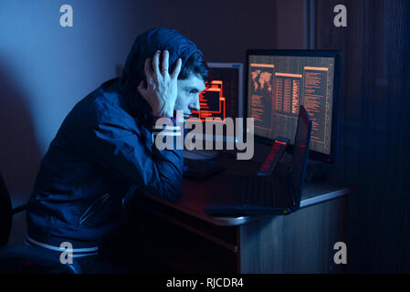 Un hacker dans une pensée de capot sur le problème de piratage ou d'infection de malware sur le fond d'écrans avec des codes dans neon light. Le concept Banque D'Images
