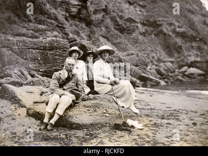 Groupe familial de quatre assis sur une plage au bord de la mer. Banque D'Images