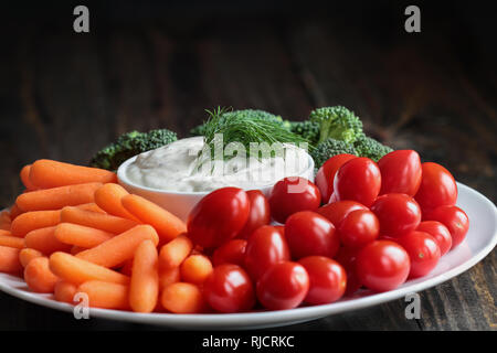 Babeurre Vinaigrette ranch maison avec de l'aneth servi avec des légumes frais, des tomates cerises, les carottes et le brocoli bébé, plus d'un mobilier rustique en bois retour Banque D'Images