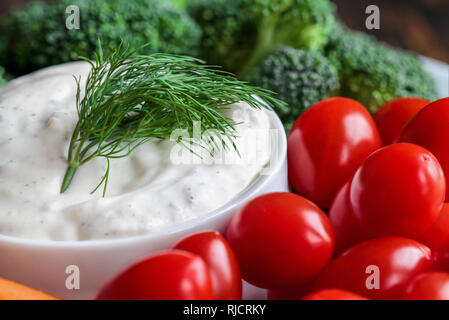 Babeurre Vinaigrette ranch maison avec de l'aneth servi avec des tomates cerises, les carottes et le brocoli bébé, sur un fond de bois rustique. Banque D'Images