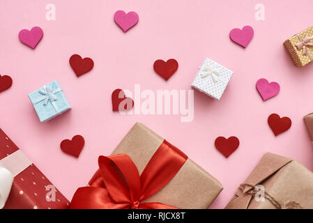 L'amour est dans l'air. Différents types de coffrets cadeaux avec du papier décoratif coeur sur fond rose. Vue d'en haut Banque D'Images