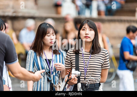 Florence, Italie - 30 août 2018 : Closeup portrait of young Asian woman face marche sur rue dans la ville historique d'écoute guide touristique avec un appareil photo Banque D'Images