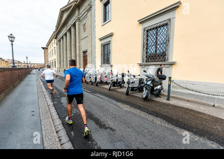 Florence, Italie - 31 août 2018 : Firenze orange jaune bâtiments colorés par Arno au cours de matin d'été en Toscane avec des hommes en marche jogging le Banque D'Images
