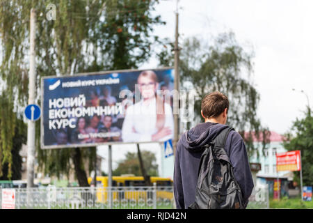 Rivne, Ukraine - le 28 juillet 2018 : Young man walking ukrainien en face de publicité politique bannière publicitaire panneau pour Ioulia Timochenko à la présidence par l'al. Banque D'Images