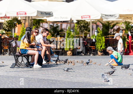 Varsovie, Pologne - 23 août 2018 : place du marché de la vieille ville historique avec la rue pavée au cours de journée d'été et les jeunes nourrir les oiseaux assis sur un banc Banque D'Images