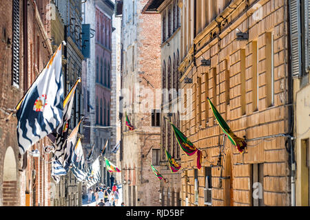 Sienne, Italie - 27 août 2018 : Street dans la vieille ville médiévale historique village de Toscane avec les gens et les touristes de nombreux drapeaux au cours de journée ensoleillée Banque D'Images
