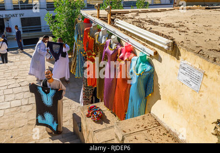 Marché sur les bords du Nil par le Temple de Kom Ombo, Haute Egypte vendre colorés traditionnels galabeyas comme souvenirs aux touristes de croisières Banque D'Images