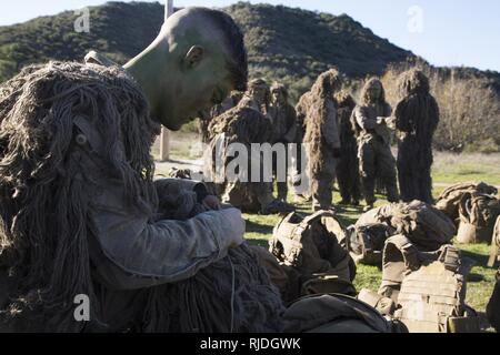 LCpl. Zachary Radack, 21 ans, de l'Aliso Viejo, Californie, a chargé professionnellement avec tireur de surveillance et d'acquisition régimentaire Company, 1er Régiment de Marines, ajuste son ghillie suit en vue d'un exercice sur le mouvement le 22 janvier 2018. RSTAC est conçue pour renforcer la maîtrise des opérations pour sniper scout exercices de niveau de service jusqu'à vivre la mission à plein feu adulte, les rapports de surveillance et de reconnaissance et d'exploitation du centre de contrôle d'un grand angle d'incendies de précision. Banque D'Images