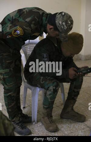Un cours sur les communications des Forces spéciales assistant instructeur observe un membre des forces de sécurité irakiennes au cours de l'essai final de l'cours en communications au Camp Taji, l'Iraq, le 17 janvier 2018. Le programme à développer et à améliorer la capacité des partenaires nationaux comprend : le leadership, l'éthique et droit de la guerre et la formation. De plus, les recrues sont enseignées la navigation terrestre, la formation médicale de base, les compétences de l'infanterie et des petites unités tactiques. Banque D'Images