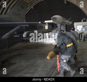 Trois aviateurs de l'US Air Force affectée à la 8e Escadron de maintenance d'aéronefs comme armes charger des membres de l'équipage, de travailler ensemble afin de charger un F-16 Fighting Falcon lors d'une génération d'aéronefs exercice à Kunsan Air Base, République de Corée, le 22 janvier 2018. Les membres des équipages de charge précisément et rapidement chargé plus de 10 avions en moins de 12 heures confirmant les aviateurs, ses capacités d'effectuer de manière compétente un concept d'opérations. Générations d'aéronefs sont simulées sur une base régulière pour confirmer la meute de maintenir la capacité de préparation aux missions en tout temps. Banque D'Images