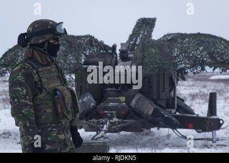 Un soldat roumain affecté à la base de la masse de l'Armée roumaine de défense aérienne, les chauves-souris noire, aide à mettre en place son équipe Oerlikon 35 mm double cannon à une gamme près de la zone d'entraînement Bemowo Piskie, Pologne, le 24 janvier 2018. La multinationale, unique, composé d'Américains, Britanniques, croate et soldats roumains servir avec la 15e Brigade mécanisée polonaise comme une force de dissuasion dans le nord-est de la Pologne à l'appui de l'OTAN vers l'amélioration de la présence. Banque D'Images