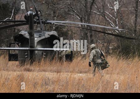 Une garde nationale armée du Missouri d'hélicoptères UH-60 avec l'équipage de l'entreprise C, 1-106e Aviation, Fort Leonard Wood, Mo., promenades à un hélicoptère Blackhawk UH-60 tandis qu'un autre soldat le prépare pour le vol au Camp Clark, dans le Nevada, Mo., le 15 janvier 2018. La société C préparé pour une soirée de récupération du personnel d'entraînement avec quatre équipages d'hélicoptères. Banque D'Images