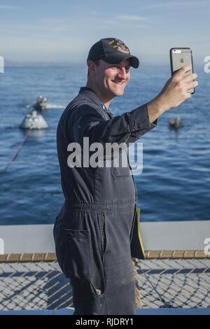 Océan Pacifique (jan. 21, 2018) Le lieutenant J.G. Myles Ramey, de Plymouth, Massachusetts prend un avec la NASA selfies Orion de l'article test l'arrière de la classe San Antonio de transport amphibie USS dock Anchorage (LPD 23). Anchorage est en cours pour soutenir le vaisseau Orion de la NASA en cours Test de récupération (6 URT-6). Banque D'Images