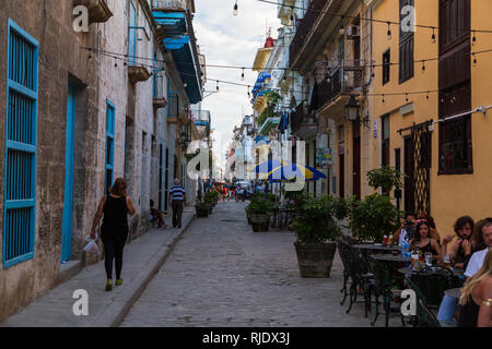 Scène dans une ruelle typique de la vieille ville de La Havane à Cuba. La population locale et les touristes à marcher le long et les Cubains à l'extérieur d'un coin repas restaurant Banque D'Images