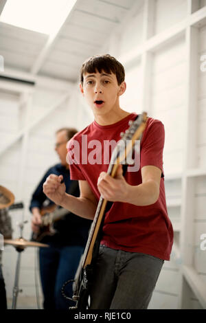 Teenage boy jouant une guitare basse avec enthousiasme. Banque D'Images