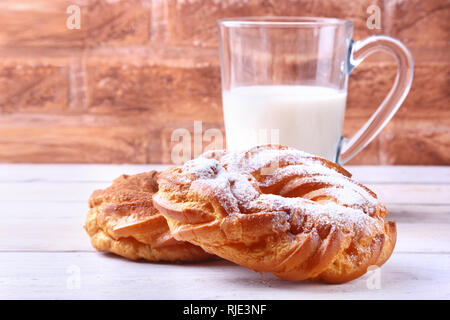 Crème au chocolat et sucre en poudre pâte de verre et joints toriques avec du lait sur la table en bois. Petit-déjeuner traditionnel. Banque D'Images