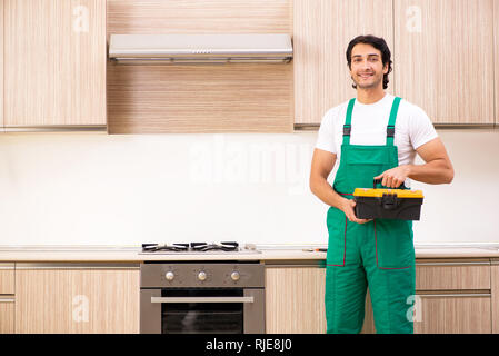 Jeune entrepreneur la réparation de four dans la cuisine Banque D'Images