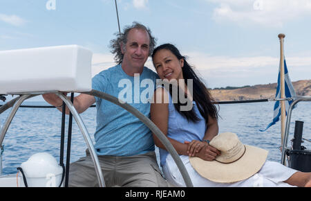 Homme et femme avec chapeau dans le cockpit de voilier avec drapeau grec Banque D'Images