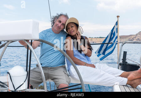 Homme et femme avec chapeau dans le cockpit de voilier avec drapeau grec Banque D'Images