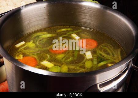 Bouillon avec carottes, oignons divers légumes frais dans un pot - frais colorés clear spring soupe. Cuisine végétarienne paysage rural bouillon Banque D'Images