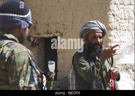 Un villageois parle d'une armée nationale afghane à l'extérieur d'un soldat des forces spéciales de contrôle de la police locale afghane dans Tagaw, district de la province d'Uruzgan, Afghanistan, le 14 avril. Les soldats soutenir l'ALP en visitant la région de contrôle afin de déterminer si des ressources, de la formation ou les actifs sont nécessaires à l'amélioration de l'ALP est capable de fournir la sécurité à l'échelle du village. Banque D'Images