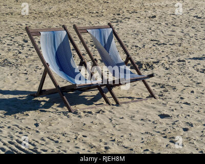 Deux terrasse en bois blanc et bleu en bandes sur une plage de sable Banque D'Images