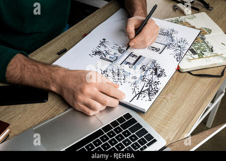 Focus sélectif de mans mains dessin dans l'album sur la table en bois à côté d'outils Banque D'Images