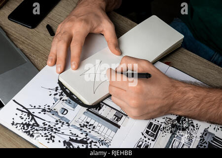 Focus sélectif de mans mains dimensions dans l'ordinateur portable sur une table en bois à côté de l'album et gadgets Banque D'Images