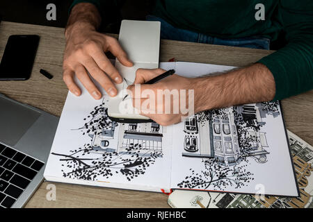 Vue de dessus du mans mains dimensions dans l'ordinateur portable sur une table en bois à côté d'albums et gadgets Banque D'Images