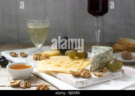 Apéritifs de différents types de fromage, raisins, noix et miel, servi avec des vins blanc et rouge. Style rustique. Banque D'Images