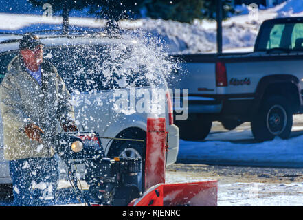 Des morceaux de neige dégel jaillit d'une souffleuse à neige au cours de l'enlèvement de la neige après une tempête hivernale au Michigan, USA. Motion à l'aide de gelée grande vitesse d'obturation. Banque D'Images