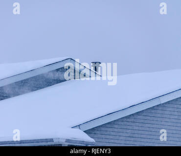 Les fortes chutes de neige ! Toits recouverts d'une épaisse couche de neige pendant une tempête de neige au début de février dans le Michigan, USA. Mist rising à partir d'un évent dans le toit. Banque D'Images