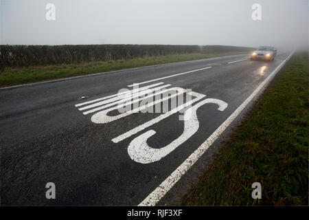 Une voiture avec ses phares sur l'approche d'un signe sur une faible bruine, brouillard journée dans Nord du Dorset England UK GO Banque D'Images