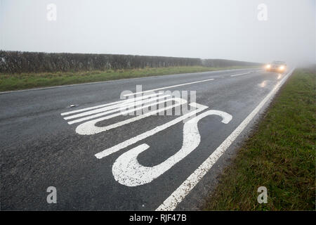 Une voiture avec ses phares sur l'approche d'un signe sur une faible bruine, brouillard journée dans Nord du Dorset England UK GO Banque D'Images