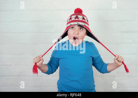 Enfant drôle avec winter hat sur fond brique Banque D'Images