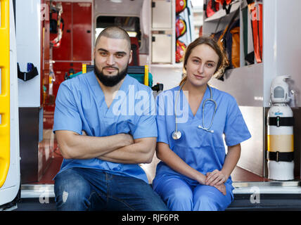 Portrait de deux ambulanciers positif assis en voiture ambulance Banque D'Images