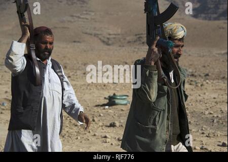 Des recrues de la police locale afghane chargée en haut d'une colline, et à leur attente que le prochain groupe de tireurs se prépare à prendre son tour de jouer lors d'une classe d'armes dans Kajran, Daykundi district province, Afghanistan, le 24 décembre. La classe fait partie d'un cours de trois semaines de l'opération dans laquelle ALP apprendre les procédures de base, le maniement des armes et d'autres compétences afin de protéger et de défendre les citoyens afghans et de maintenir la stabilité dans la région. Banque D'Images