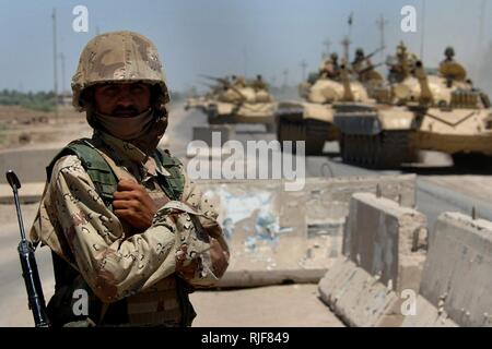 Un soldat de l'armée irakienne est la garde tandis que les soldats de l'armée irakienne à partir de la 9e Division Mécanisée passent par un point de contrôle routier dans Mushahada, l'Iraq, en route au Camp Taji, l'Iraq, le 18 mai 2006. Banque D'Images