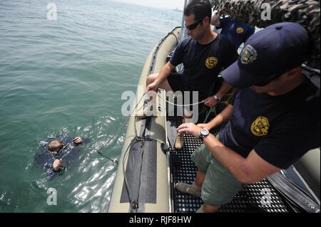 Le Maître de 2e classe de la marine Justin Cavitt, gauche, un plongeur de la Marine ; Maître de 1re classe Michael McClelland, un plongeur de la Marine ; et le Maître de 1re classe Brandon Perry, un plongeur, tous affectés à l'unité mobile de récupération et de plongée 1, mener une lutte contre le terrorisme sur la protection de la force d'inspection de plongée un remorqueur bateau avant la saisie d'un remorqueur de port de Bahreïn. MDSU-1 mène des opérations de plongée de l'ATFP pour assurer la sûreté et la sécurité des navires entrant et sortant dans le cadre d'opérations de sécurité maritime. Banque D'Images