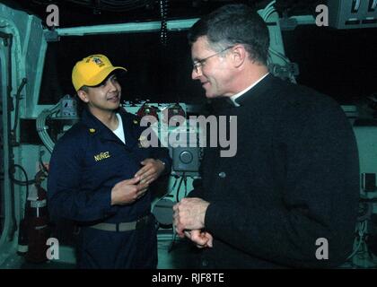 Mgr Timothy Broglio, Archevêque pour les services militaires parle avec le Lieutenant Cmdr. Jason B. Nunez sur le pont du navire d'assaut amphibie USS Iwo Jima. L'archevêque a visité l'équipage pendant deux jours pour se familiariser avec la vie en mer et l'impact de l'aumônier de la Marine américaine a Corps marins sur des vies. Banque D'Images