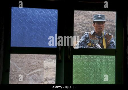 Un membre de la police en uniforme afghane monte la garde à l'extérieur d'un prix dans le cadre d'un appel privé forer en une classe dans Kajran Daykundi district, province, Afghanistan, le 11 février. La classe fait partie d'un cours de formation de trois semaines conçu pour être admissible AUP de charger la police locale afghane des candidats dans les procédures de police de base, le maniement des armes et les autres compétences nécessaires pour protéger et défendre les citoyens afghans. Banque D'Images