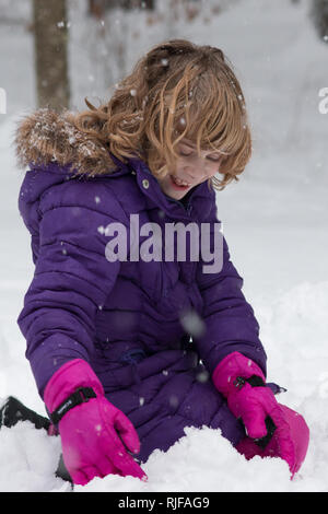 Une fillette de 8 ans jouer dans la neige. Banque D'Images