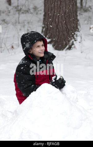 Un 11-année-vieux garçon jouer dans la neige. Banque D'Images