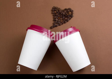 Vue de dessus du papier blanc pour tasses et coeur fait avec des grains de café, blanc des maquettes en papier, copie espace, fond brun Banque D'Images