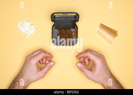 Vue partielle de jeune homme posant avec le tabac fort isolé sur le jaune Banque D'Images