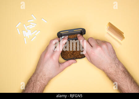 Vue partielle de l'homme avec le tabac fort isolé sur le jaune Banque D'Images