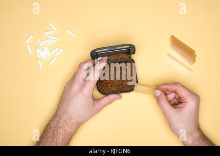 Portrait de l'homme avec la confection de cigarettes tabatière isolé sur le jaune Banque D'Images